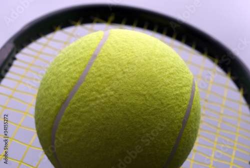 Big yellow tennis ball on a racket