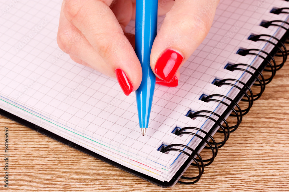 woman's hand and notepad on wooden background woman's hand and notepad on wooden background