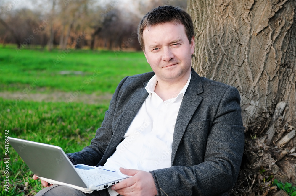 Businessman with laptop working under a tree Businessman with laptop working under a tree