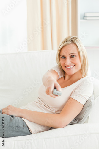 Portrait of a woman using a remote with a knowing smile