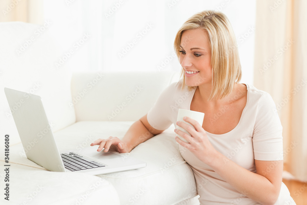 Woman holding a mug while using a laptop Woman holding a mug while using a laptop