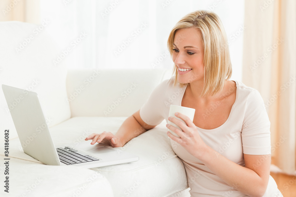 Woman holding a mug while using a notebook Woman holding a mug while using a notebook