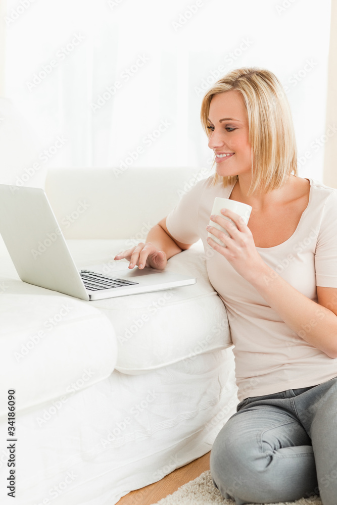 Portrait of awoman holding a mug while using a notebook Portrait of awoman holding a mug while using a notebook
