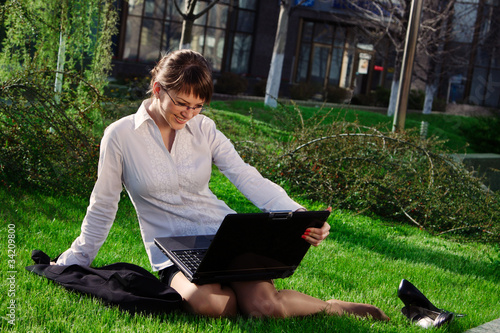 Woman lying on grass with laptop