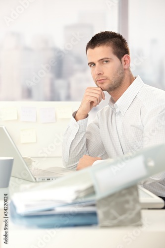 Young casual office worker sitting at desk