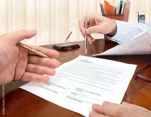 Male hands with pens signing a contract.