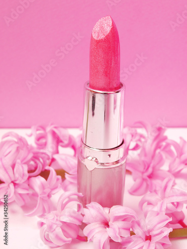 Pink sparkle lipstick and pink flowers on pink background