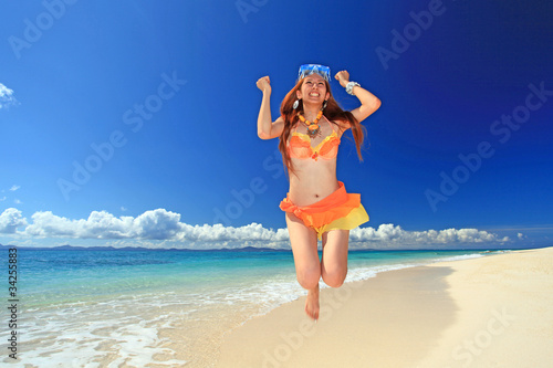 波打ち際でジャンプをする笑顔の女性