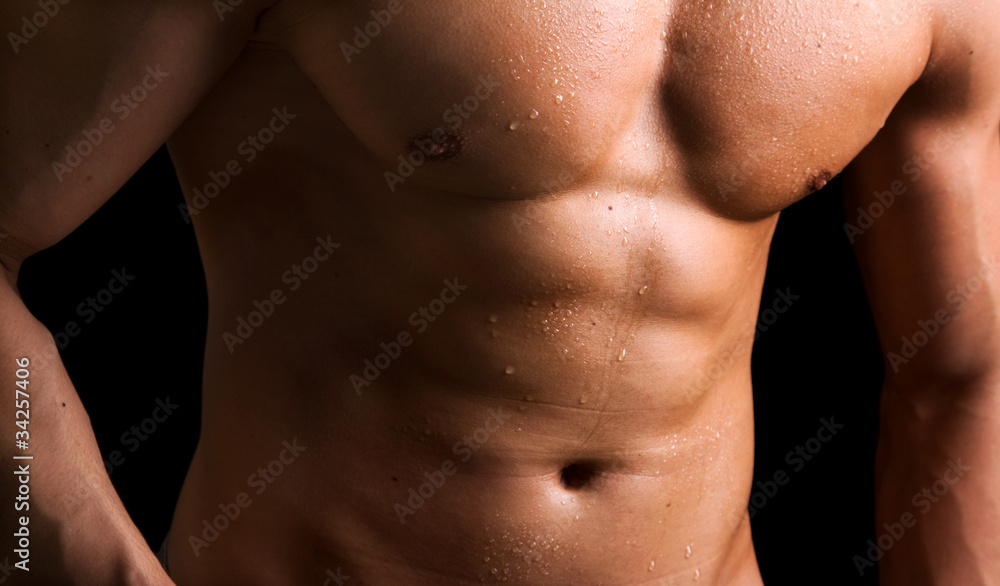 Muscled naked torso on black background