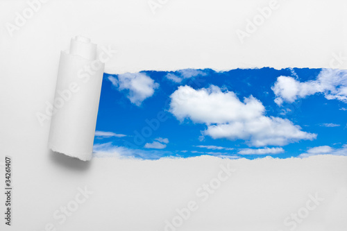Ripped paper showing blue sky and clouds