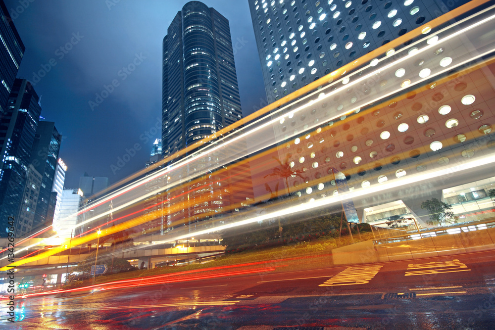 Obraz premium traffic light trails in the street by modern building