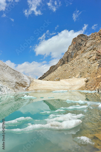 Mountain lake with ice, snow and clouds