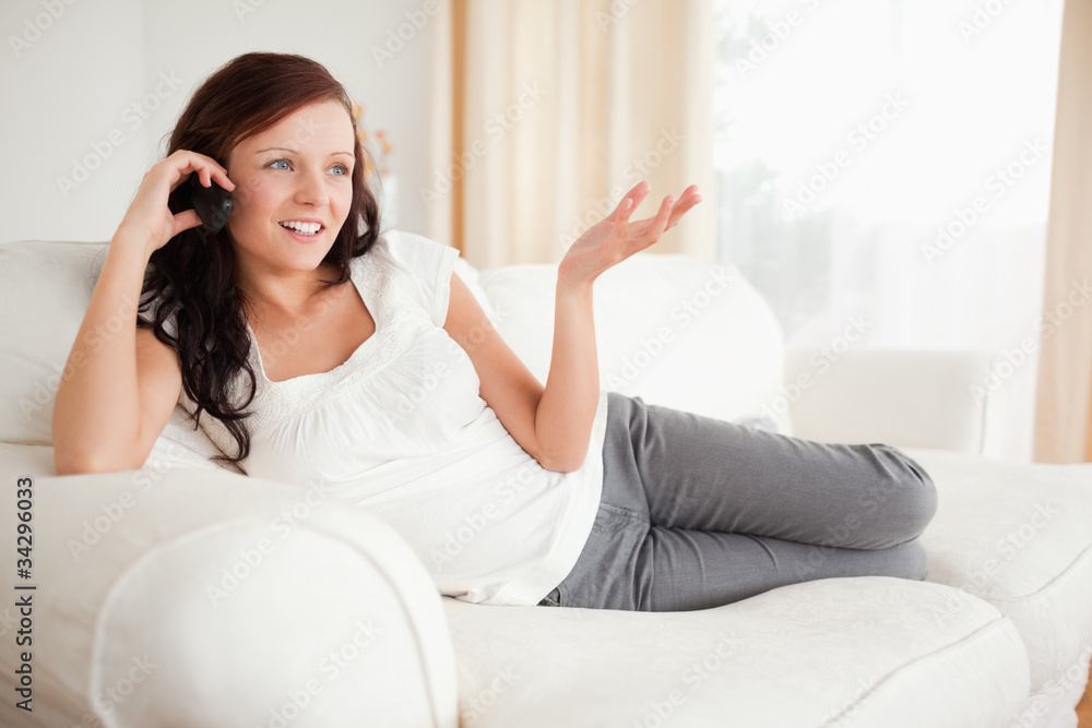Red-haired woman relaxing on a sofa phoning Red-haired woman relaxing on a sofa phoning