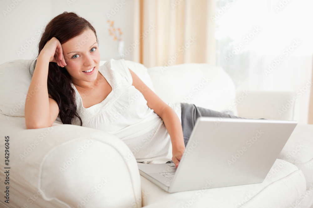 Red-haired woman relaxing on a sofa surfing the internet looking Red-haired woman relaxing on a sofa surfing the internet looking