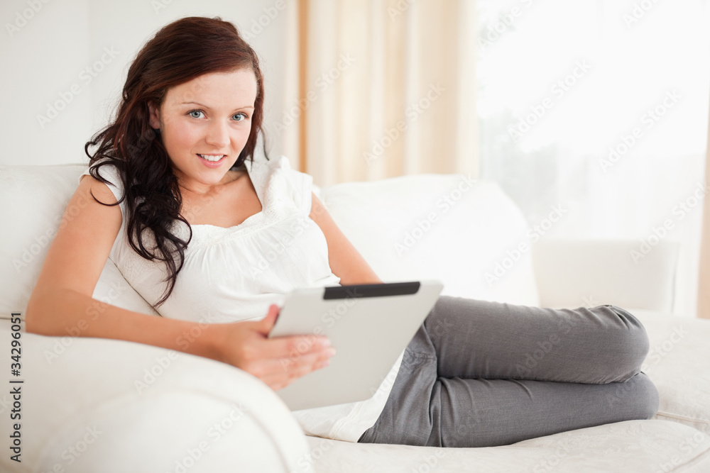 Beautiful woman relaxing on a sofa surfing the internet with a Beautiful woman relaxing on a sofa surfing the internet with a
