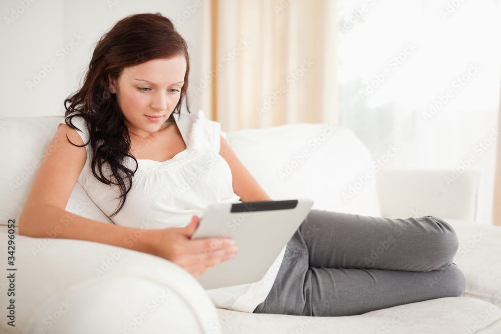Beautiful woman relaxing on a sofa surfing the internet with a Beautiful woman relaxing on a sofa surfing the internet with a
