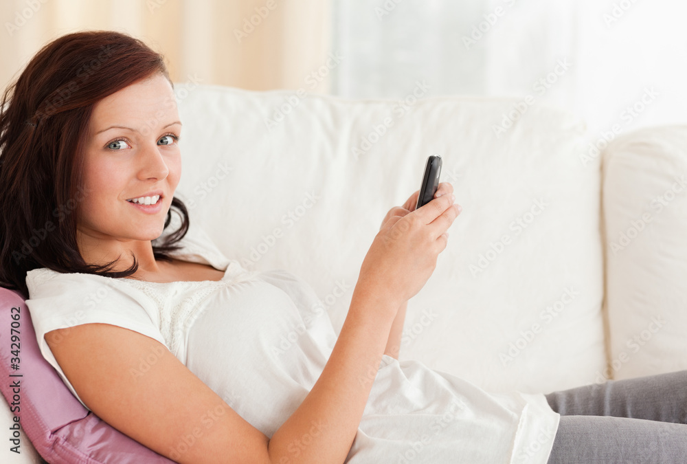 Red-haired Woman texting while sitting on the sofa Red-haired Woman texting while sitting on the sofa