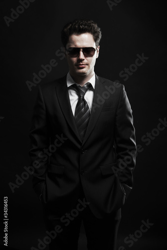 Portrait of a young businessman in sunglasses and a black suit