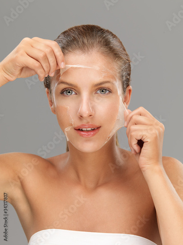 young woman taking off peeling mask photo