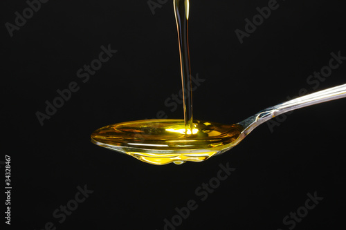 olive oil in spoon on black background