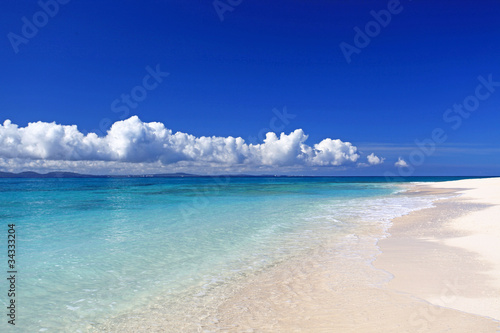 水納島の澄んだサンゴ礁の海と空に浮かぶ白い雲 © sunabesyou