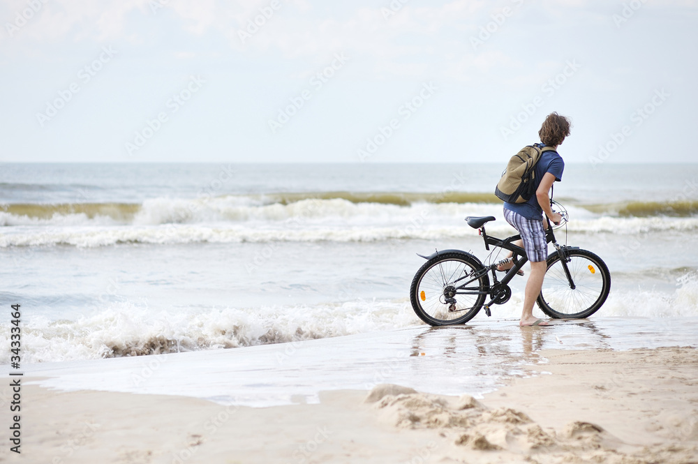 Young man bicycling along al beach, Baltic sea