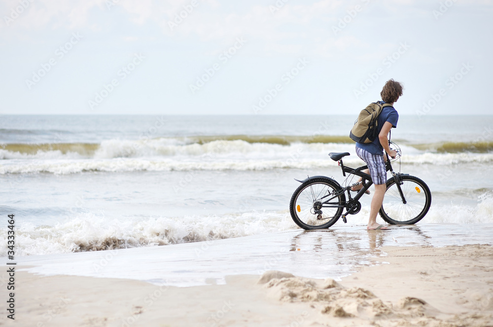 Fototapeta premium Young man bicycling along al beach, Baltic sea