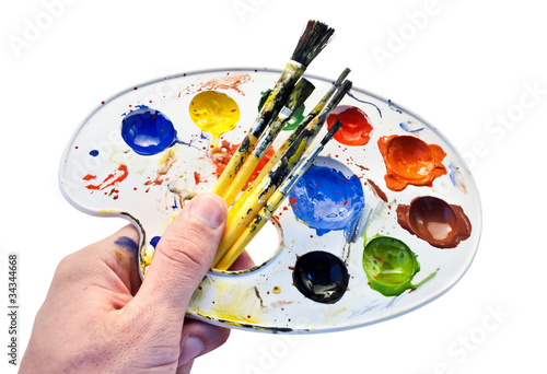 Set of brushes and a colorful paint in man`s hand.