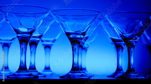 Wineglasses arranged in rows on the table in blue light