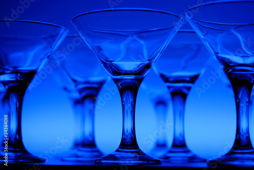 Wineglasses arranged in rows on the table in blue light