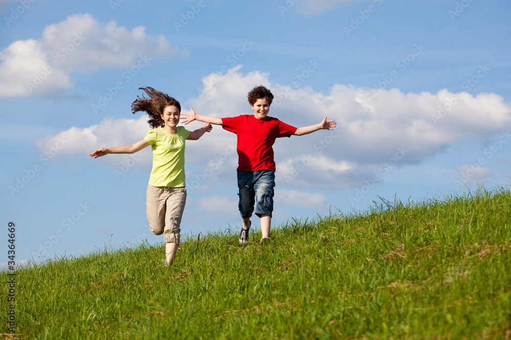 Girl and boy running, jumping against blue sky Girl and boy running, jumping against blue sky