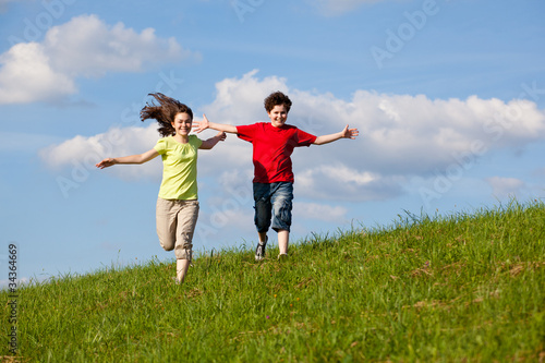 Girl and boy running, jumping against blue sky