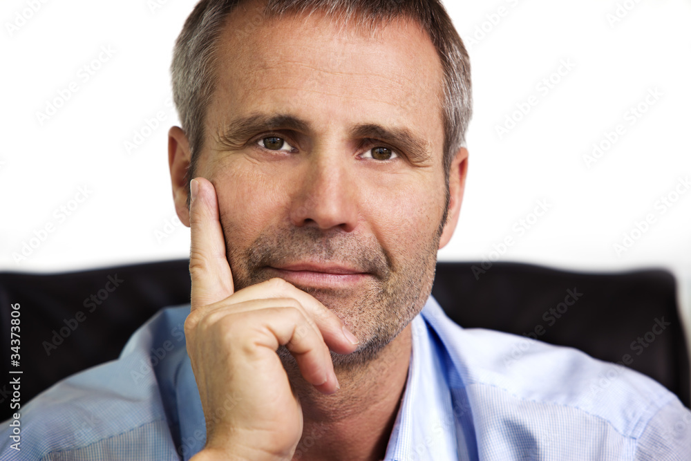 Close-up of confident businessman resting chin on hand.