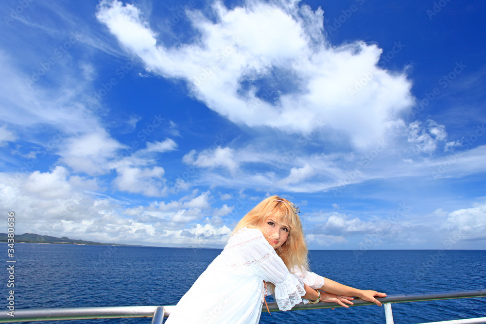 フェリーの上から伊平屋島の風景を楽しむ笑顔の女性