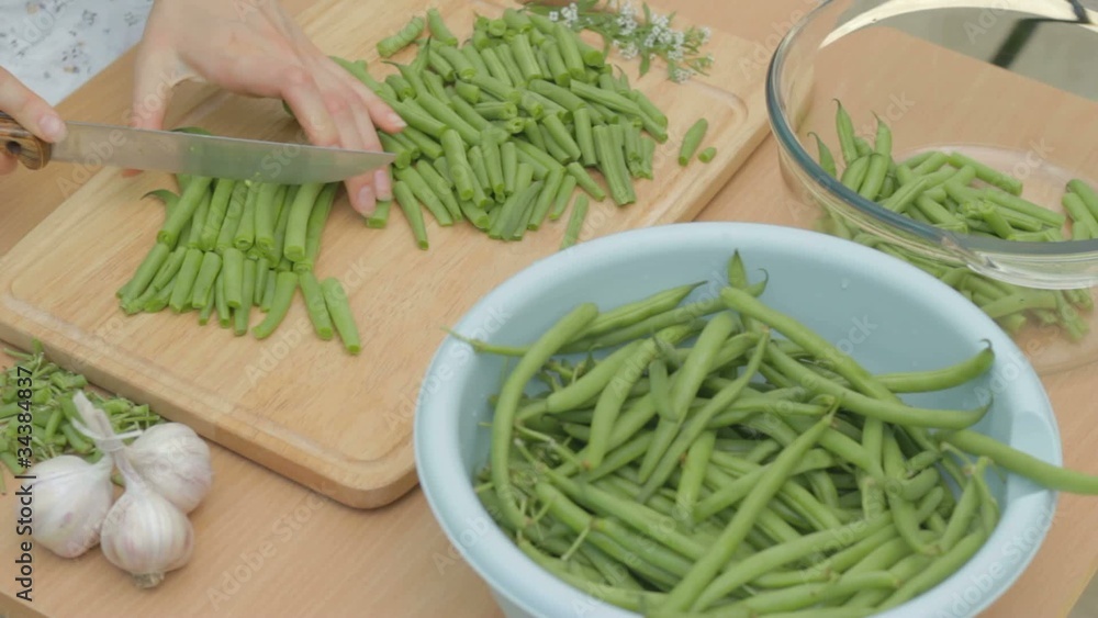Slicing fresh green string beans on wooden chopping board Slicing fresh green string beans on wooden chopping board