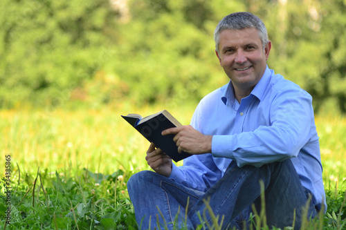 portrait of a man in a park with a book