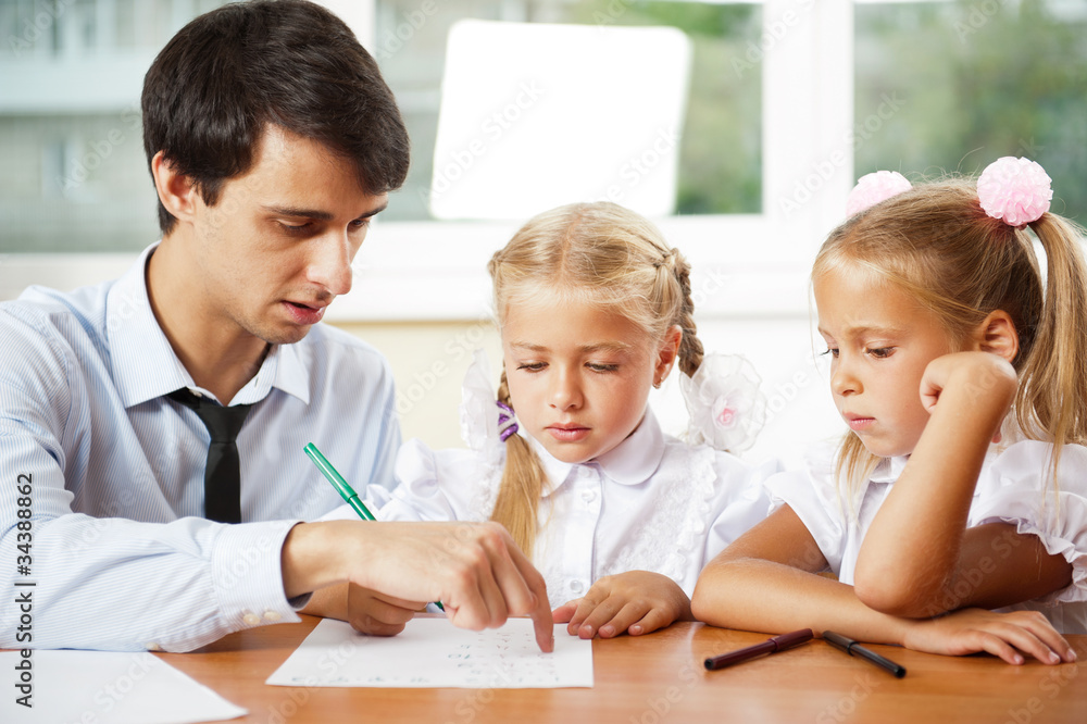 Teacher helping elementary school pupils with their tasks Teacher helping elementary school pupils with their tasks