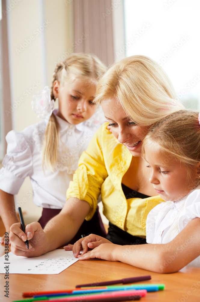 Young pretty teacher helping her little students in classroom Young pretty teacher helping her little students in classroom