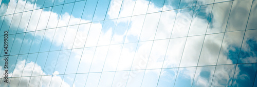 white clouds and azure sky reflected in mirror windows