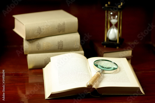Books with magnifying glass and hourglass