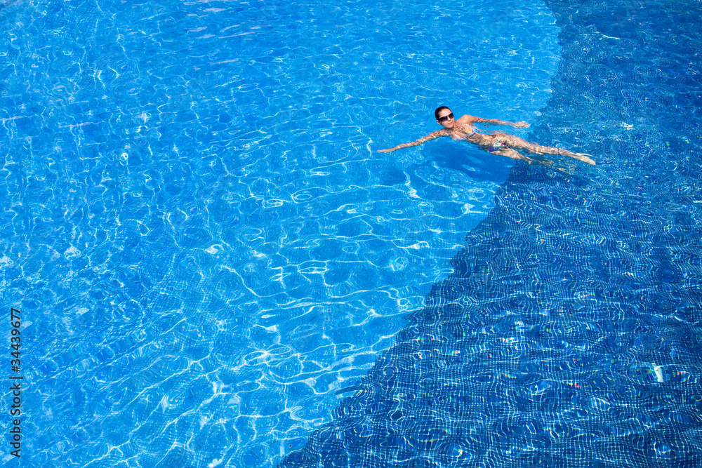 Tanned young europen woman swimming in pool