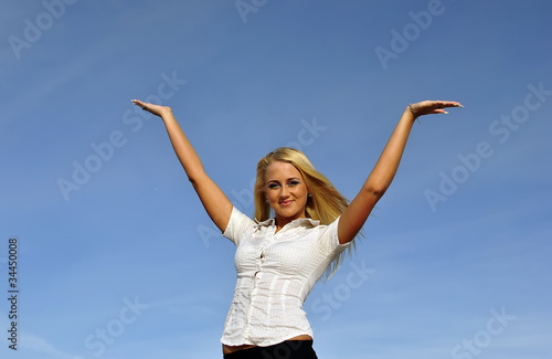 Blonde girl in a white shirt against the sky. Space for text