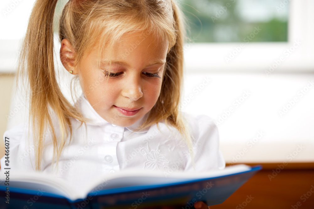 Image of smart child reading interesting book in classroom Image of smart child reading interesting book in classroom