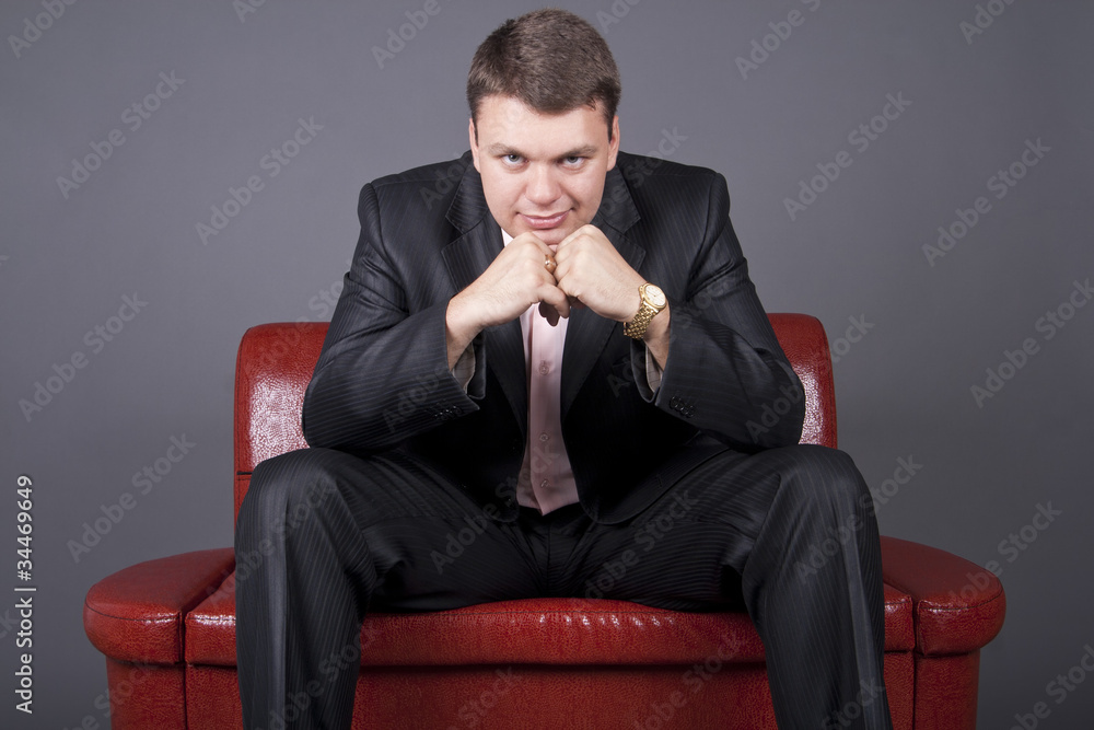 thoughtful guy in a suit sitting on a red couch thoughtful guy in a suit sitting on a red couch