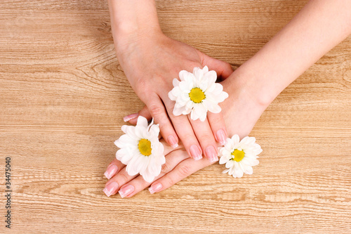 beautiful woman's hands and flower on wooden background