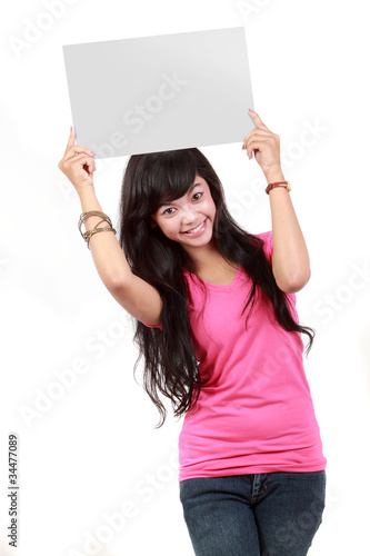 Portrait of a cute young woman holding a blank card up on her fa