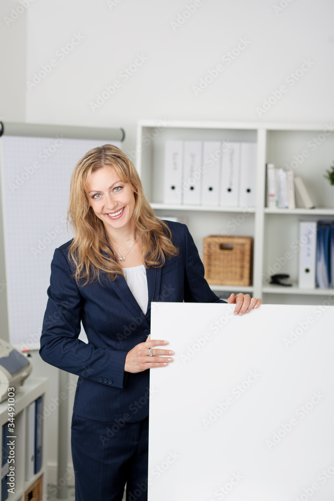 lächelnde frau im büro zeigt eine weiße tafel lächelnde frau im büro zeigt eine weiße tafel