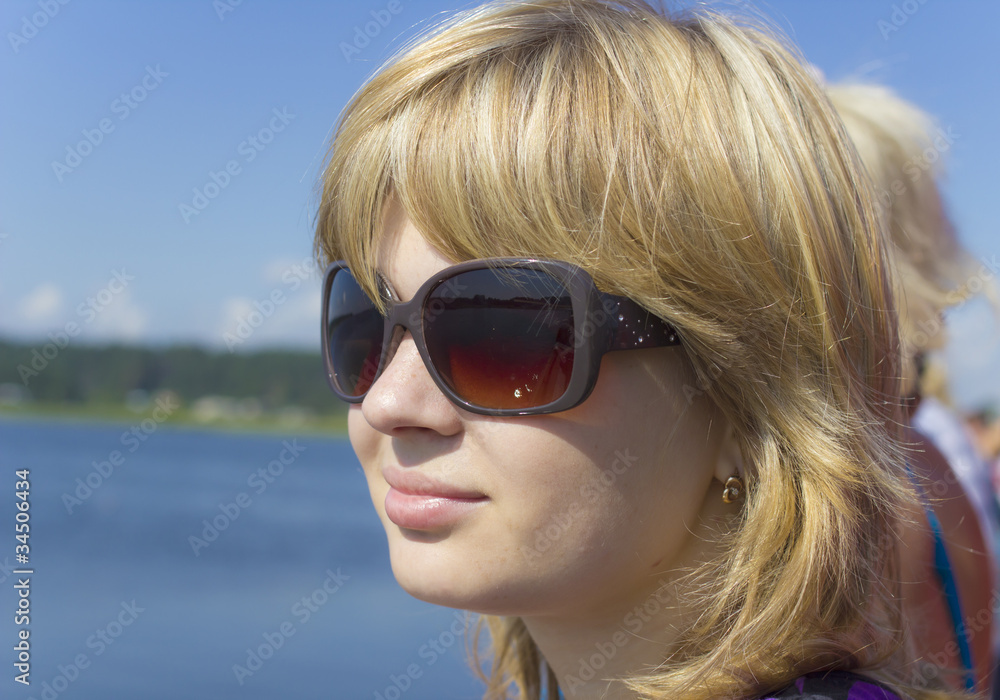 Portrait of young girl in sunglasses looking at the water Portrait of young girl in sunglasses looking at the water