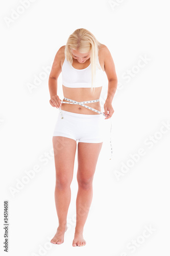 Young blond woman measuring her waist