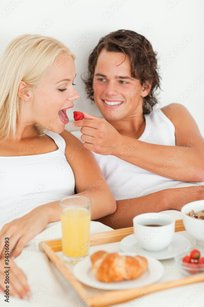 Portrait of handsome man giving a strawberry to his girlfriend Portrait of handsome man giving a strawberry to his girlfriend